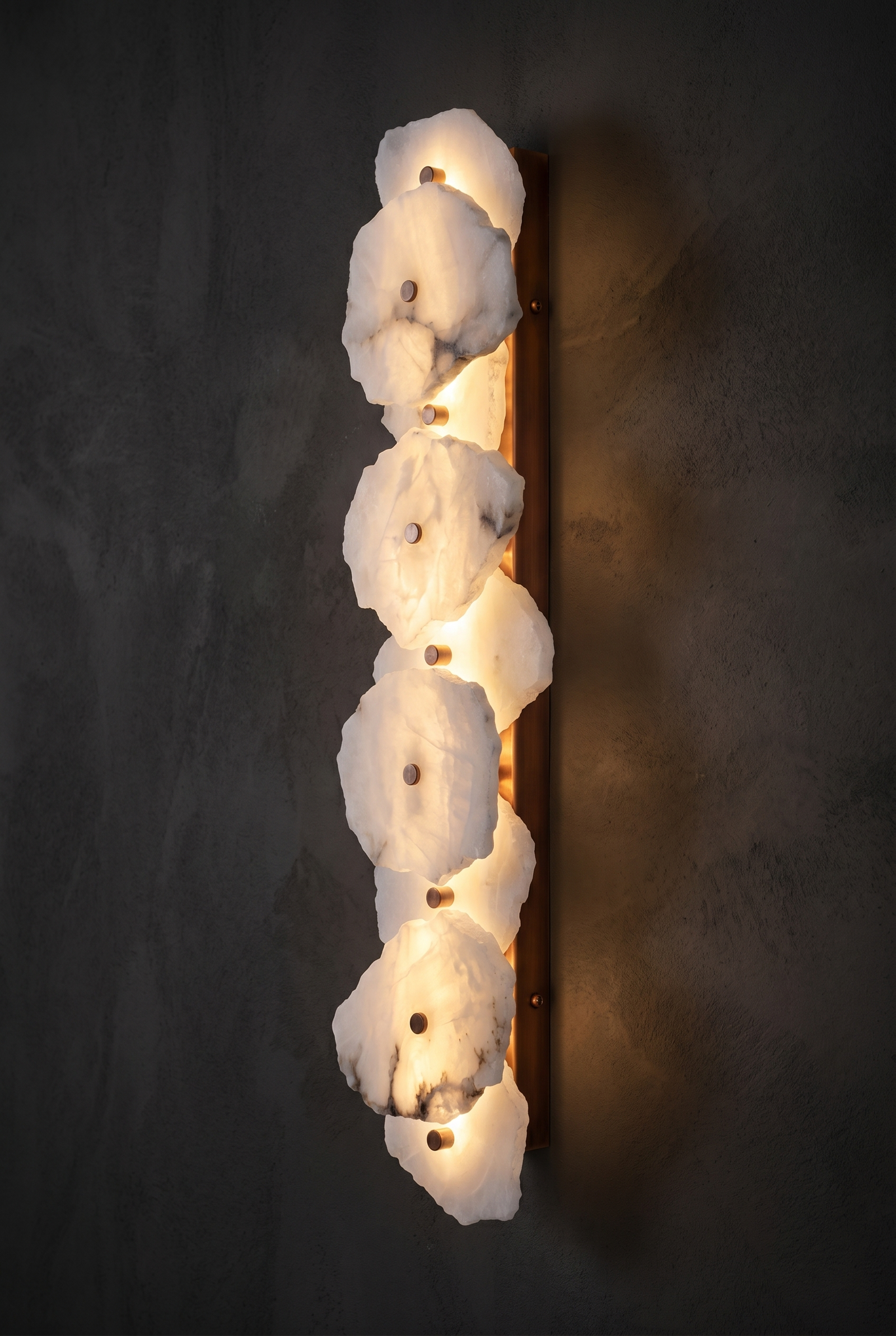 Spanish Marble Linear alabaster and copper wall sconce glowing on a dark wall
