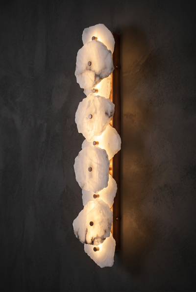 Spanish Marble Linear alabaster and copper wall sconce glowing on a dark wall